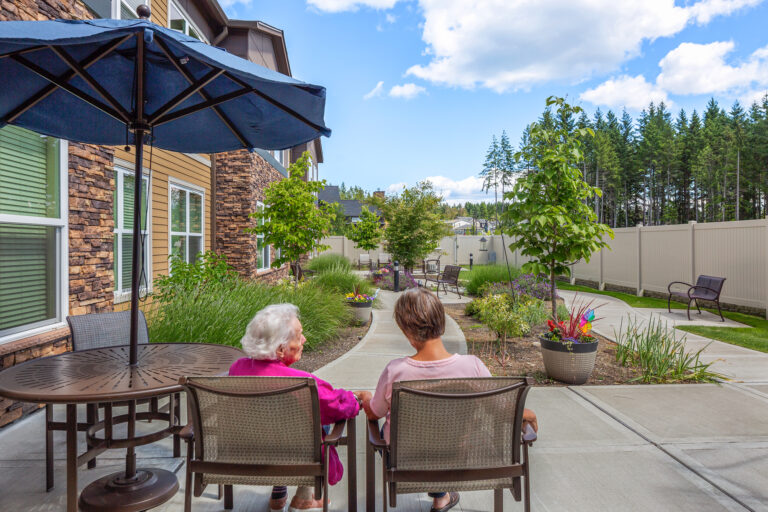 A resident and family member spending time together in the Assisted Living courtyard at Heron's Key.