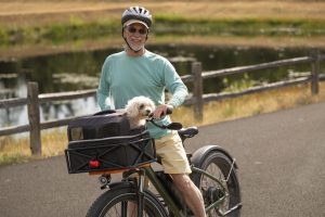 Man on his bike on the path around the pond at herons key with his dog in the basket 